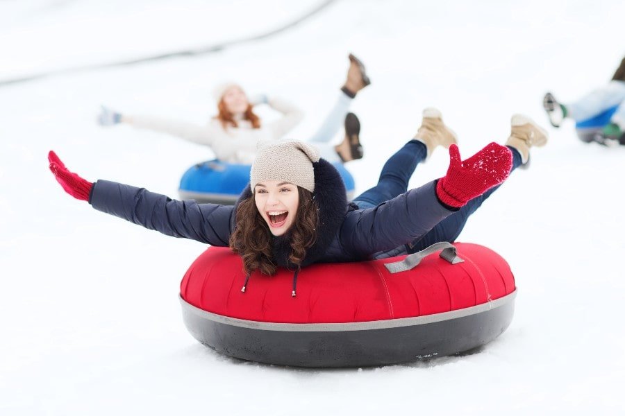 girl sliding down a ski run on a snow tube